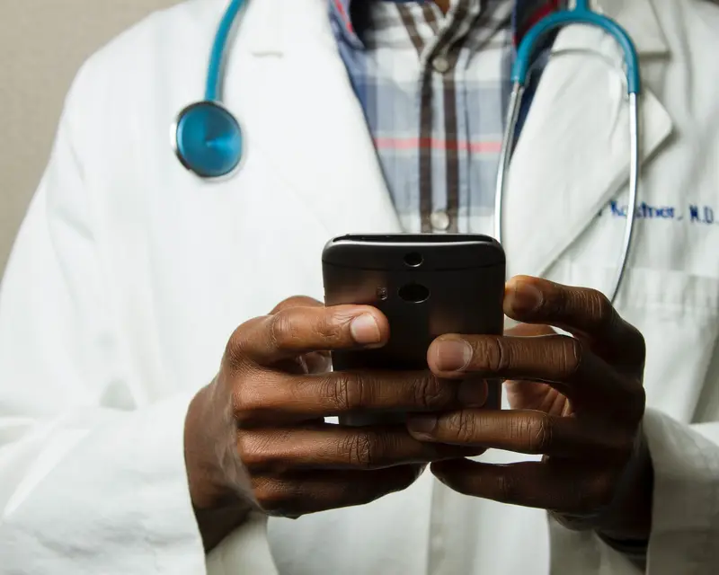 A doctor holding a smartphone, ready for a video visit